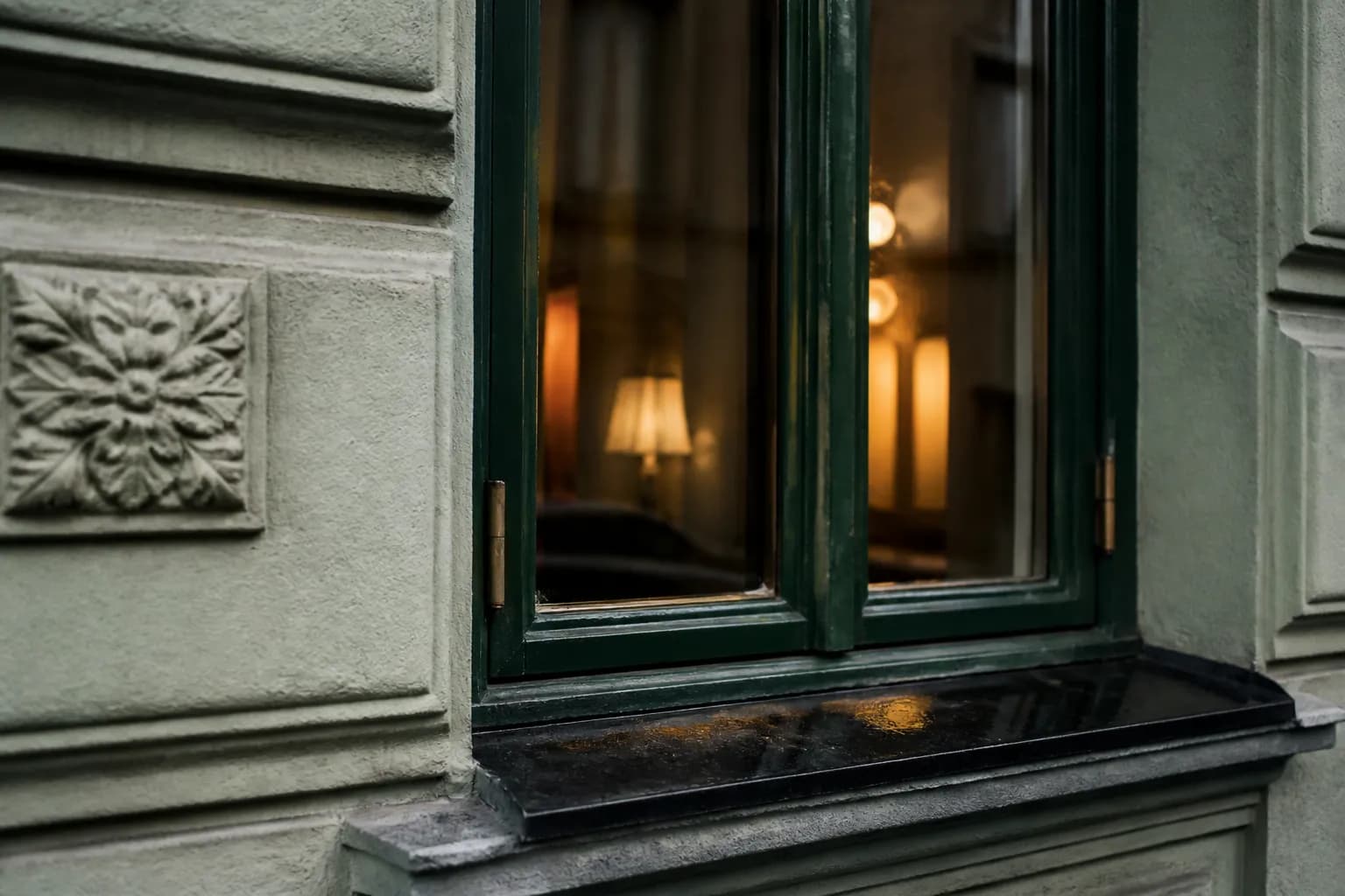 Detail einer Berliner Altbaufassade mit holzgefasstem Fenster und Messingbeschlag