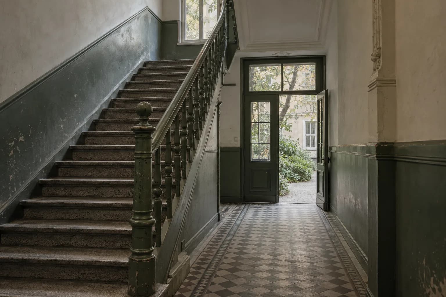 Illustratives Berliner Altbau-Treppenhaus mit grüner Tür zum Hof
